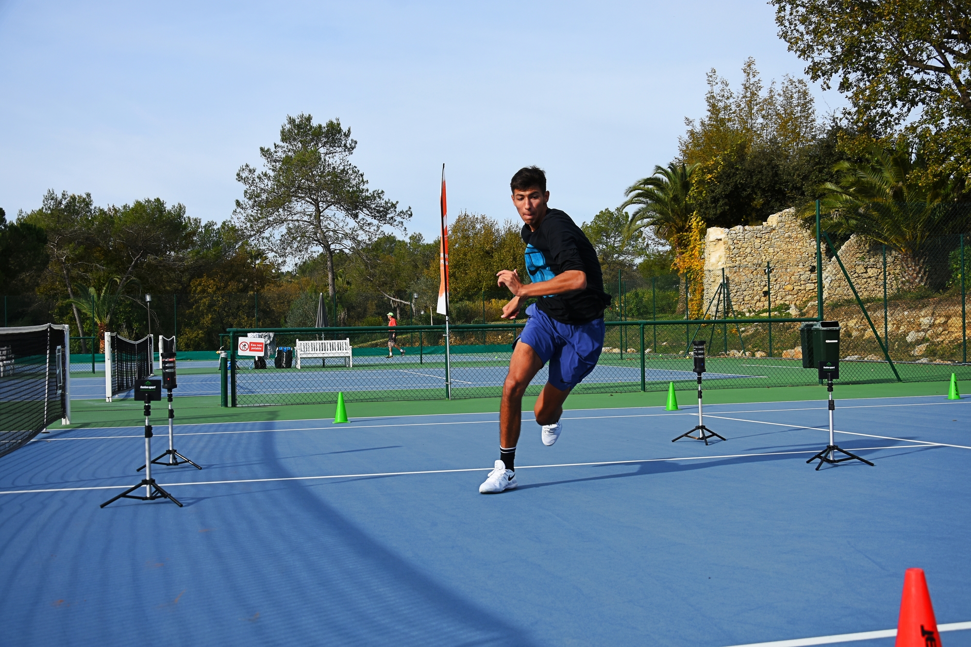 Tennis player executing a split-step and lateral footwork drill during ball machine practice